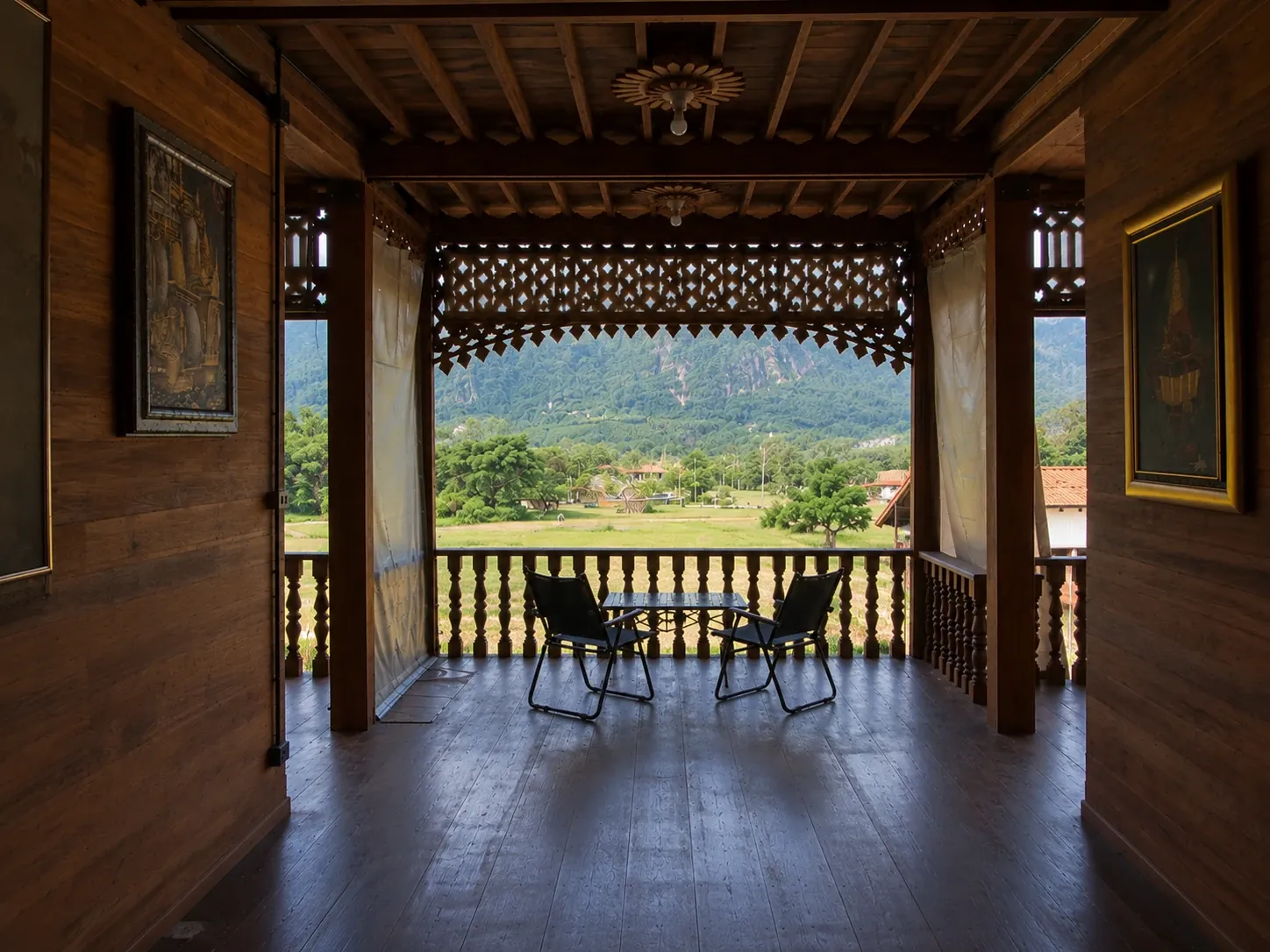 The upper chaan: open teak terrace with carved lattice and a view of the limestone ridge